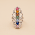 Anillo ajustable de acero inspirado en los chakras, visto de frente con sus colores sobre fondo beige