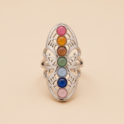 Anillo ajustable de acero inspirado en los chakras, visto de frente con sus colores sobre fondo beige