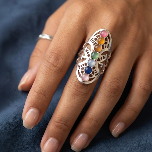 Anillo ajustable de acero con detalles de color inspirado en los chakras en la mano de una modelo