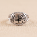 Anillo ajustable de Plata 925 con diseño de flores silvestres visto de frente sobre fondo beige