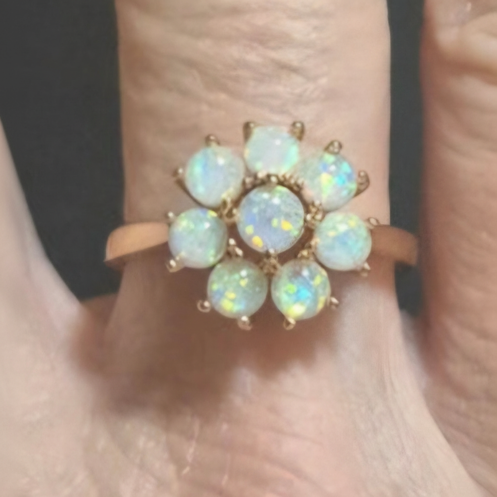 Anillo Flor dorado con ópalo sintético blanco en la mano de una modelo