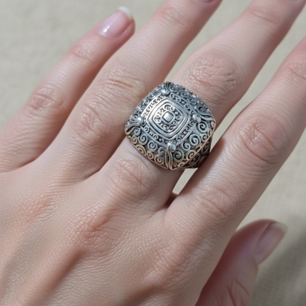 Anillo Sello Volutas de acero con baño de rodio en la mano de una modelo