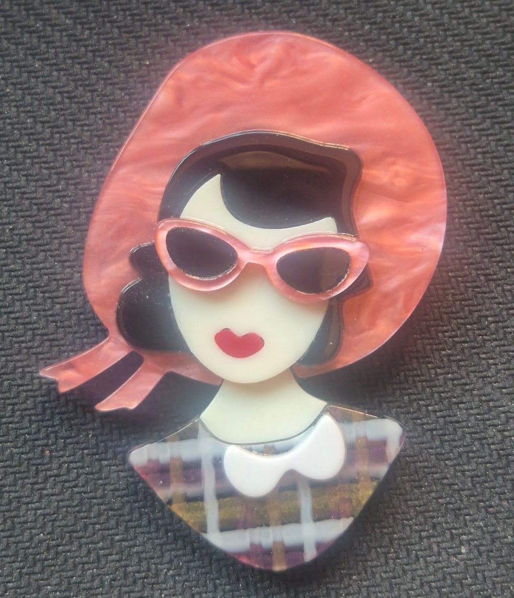 Broche retro de acrilico de busto mujer con gafas de sol rosas.