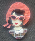 Broche retro de acrilico de busto mujer con gafas de sol rosas.