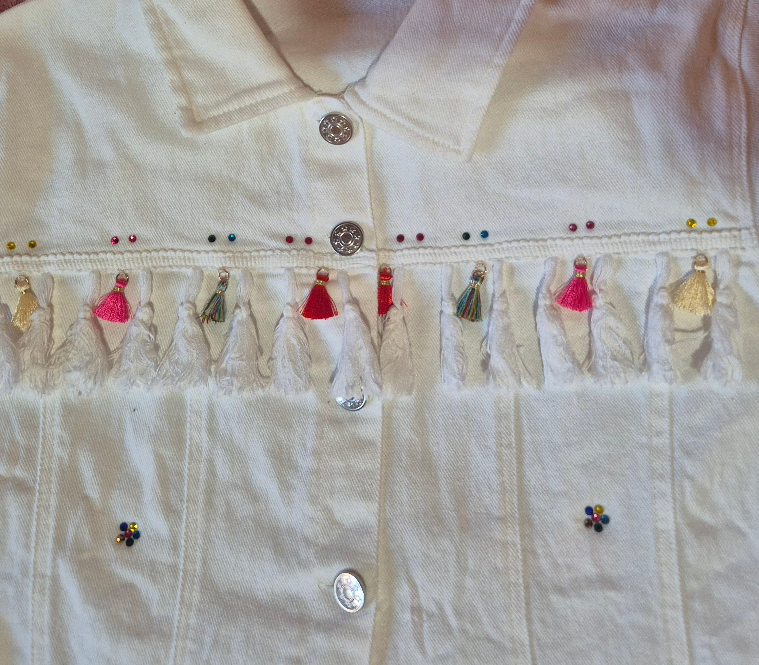 Vista lateral chaqueta denim blanca artesanal con borlas de colores | vaqueraspain