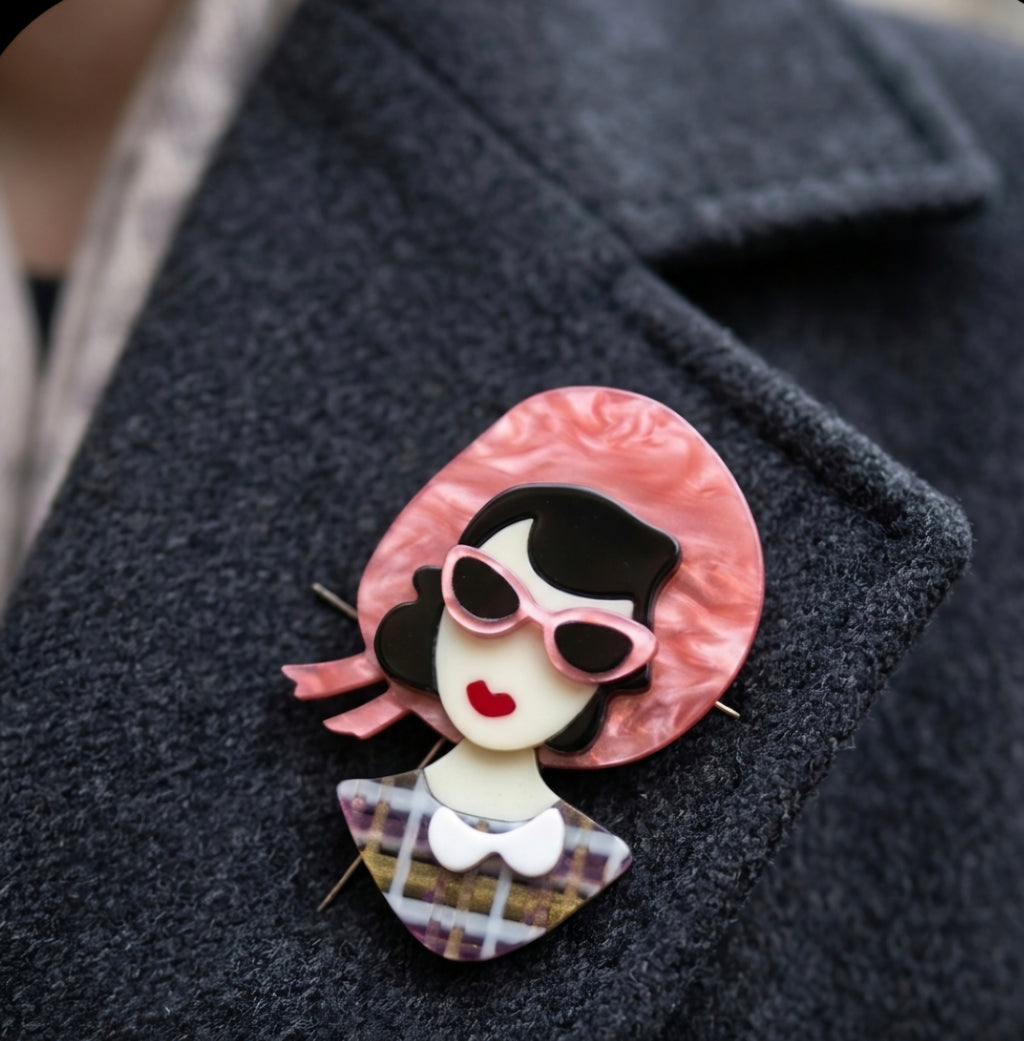 Broche retro de acrilico de busto mujer con gafas de sol rosas.